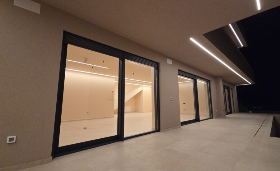 Modern luxury villa terrace with large glass doors and ambient night lighting