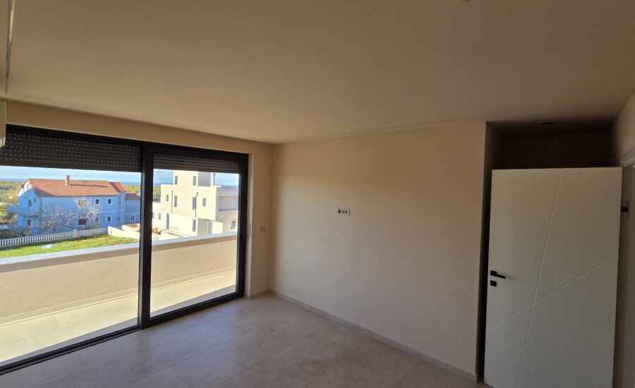 Spacious open-plan living area with large windows and neutral flooring.