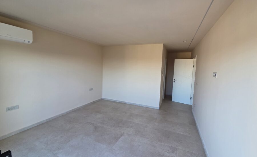 Spacious open-plan living area with large windows and neutral flooring.