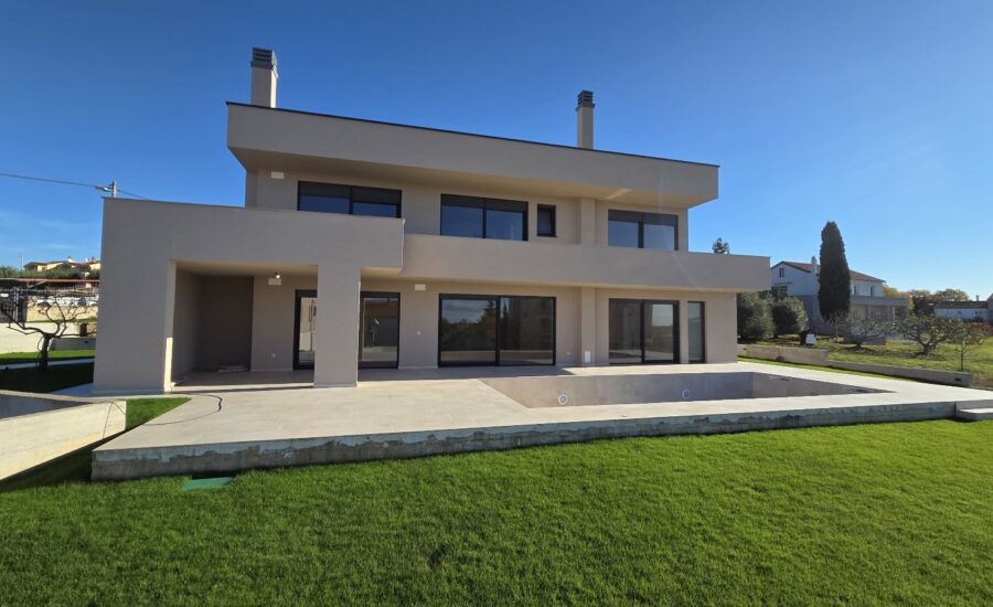 Modern two-story house with pool and large glass windows.
