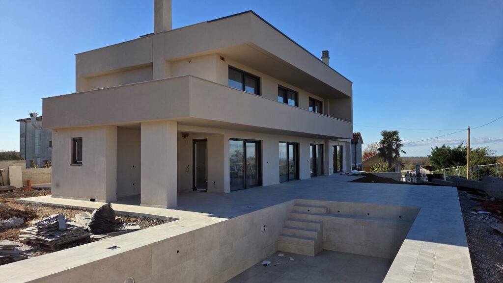 Modern two-story house with pool and large glass windows.