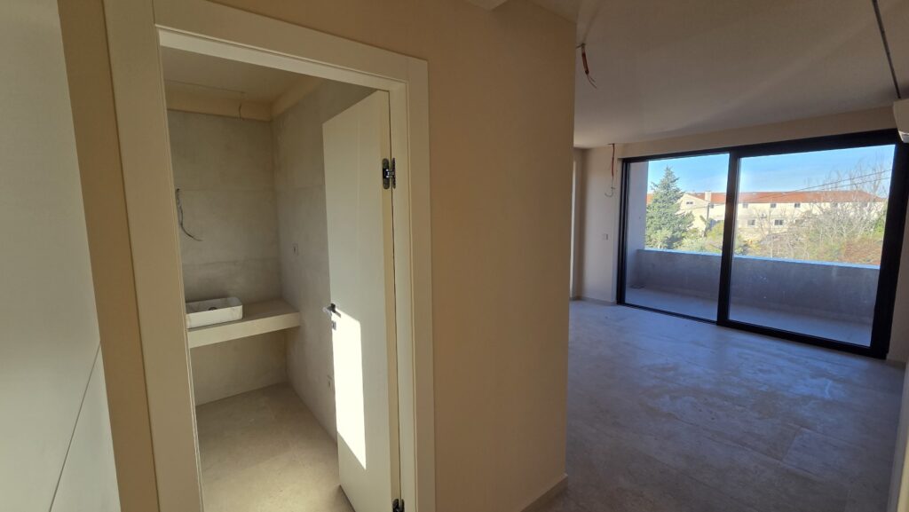 Contemporary hallway featuring a sleek staircase, light floor tiles, and access to multiple rooms.