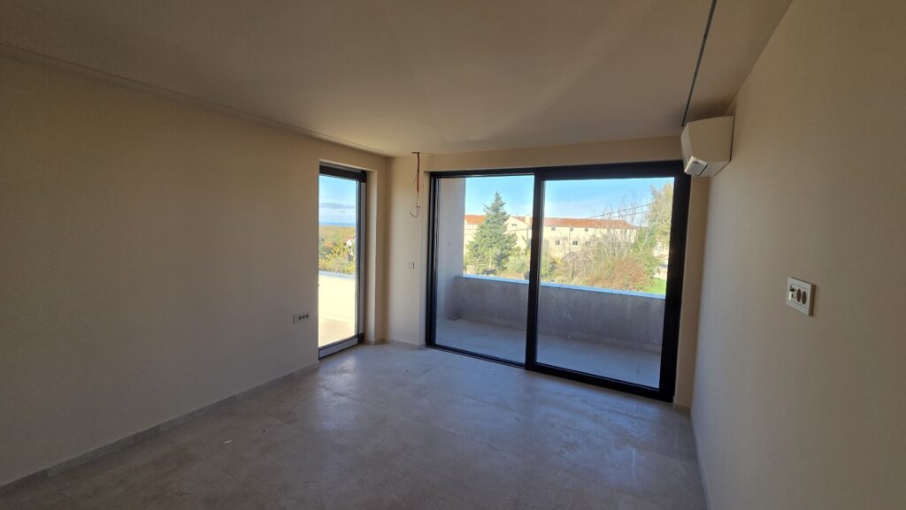 Open modern interior featuring light stone-look tiles, large windows for natural light, and a staircase connecting to the upper level.”