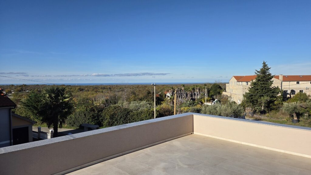 Modern house façade with glass balconies and panoramic sea view.